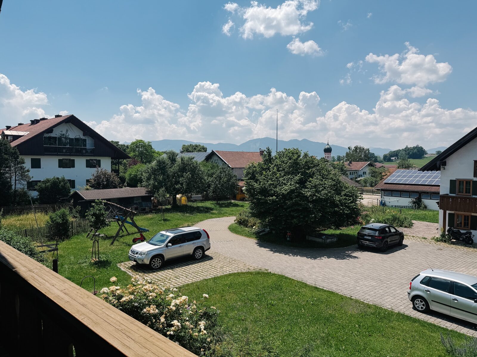 Balkonblick über Uffing mit Kirchturm und Alpenpanorama
