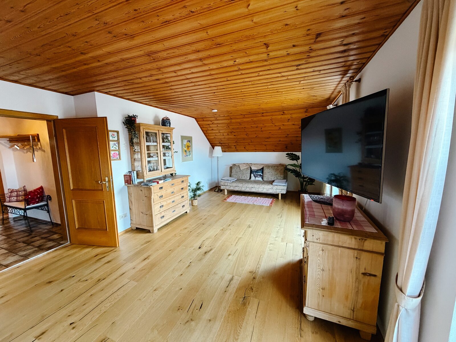 Großzügiger Wohnbereich mit Flachbild-TV und hellen Holzmöbeln